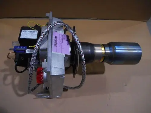 Remeha-Komponente mit metallischem Gehäuse, Schlauchleitungen und elektrischen Anschlüssen. Das Teil hat einen konischen Auslass und ist auf einer Pappe platziert.